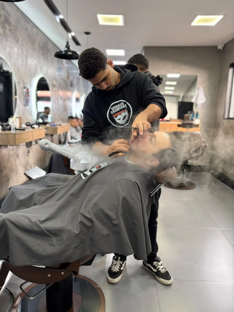 Barbeiro da Champions cuidando da barba de um cliente com vapor
